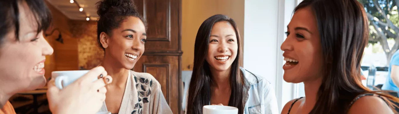 Groupe de femmes souriantes partageant un café, symbole de convivialité et d’intégration sociale pour les nouveaux arrivants au Luxembourg
